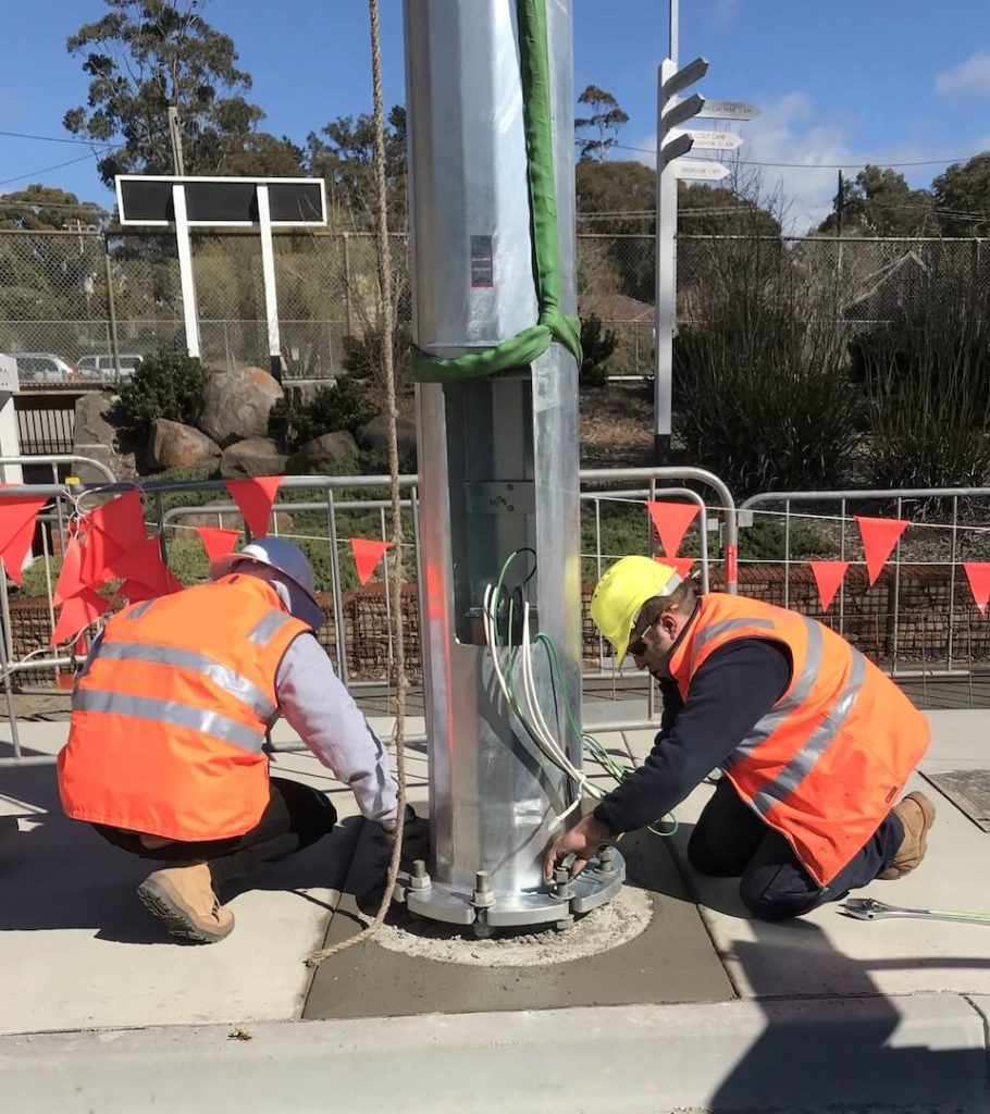 electricians installing electrical pole roadside