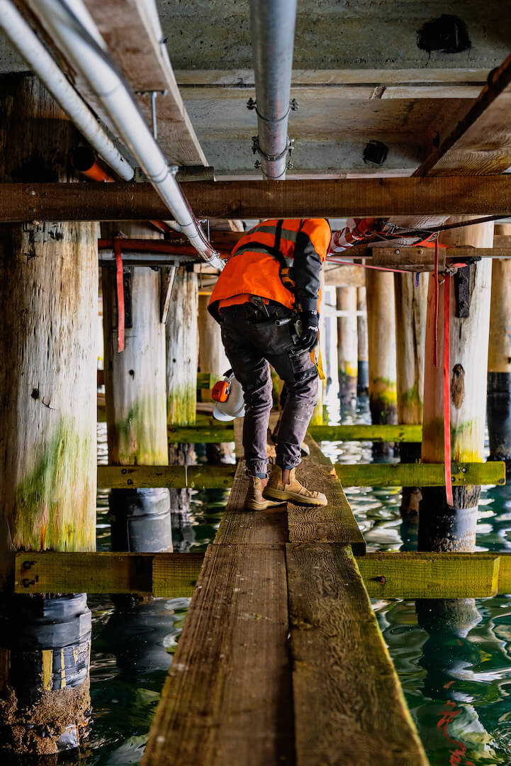 Plumber walking under pier at a port do perform industrial plumbing works